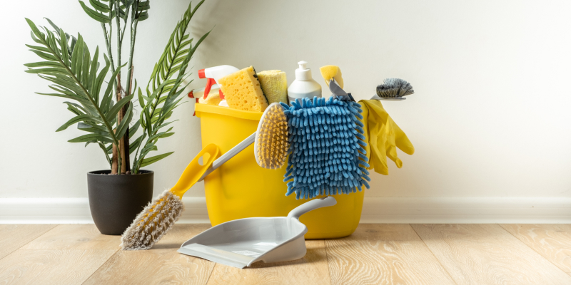 Household cleaning kit with yellow bucket, red basin, detergent bottles, gloves, sponges, and brushes