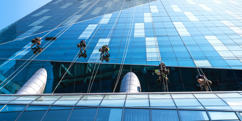 Professional rope access technicians cleaning building glass using effective high-rise window cleaning tips.